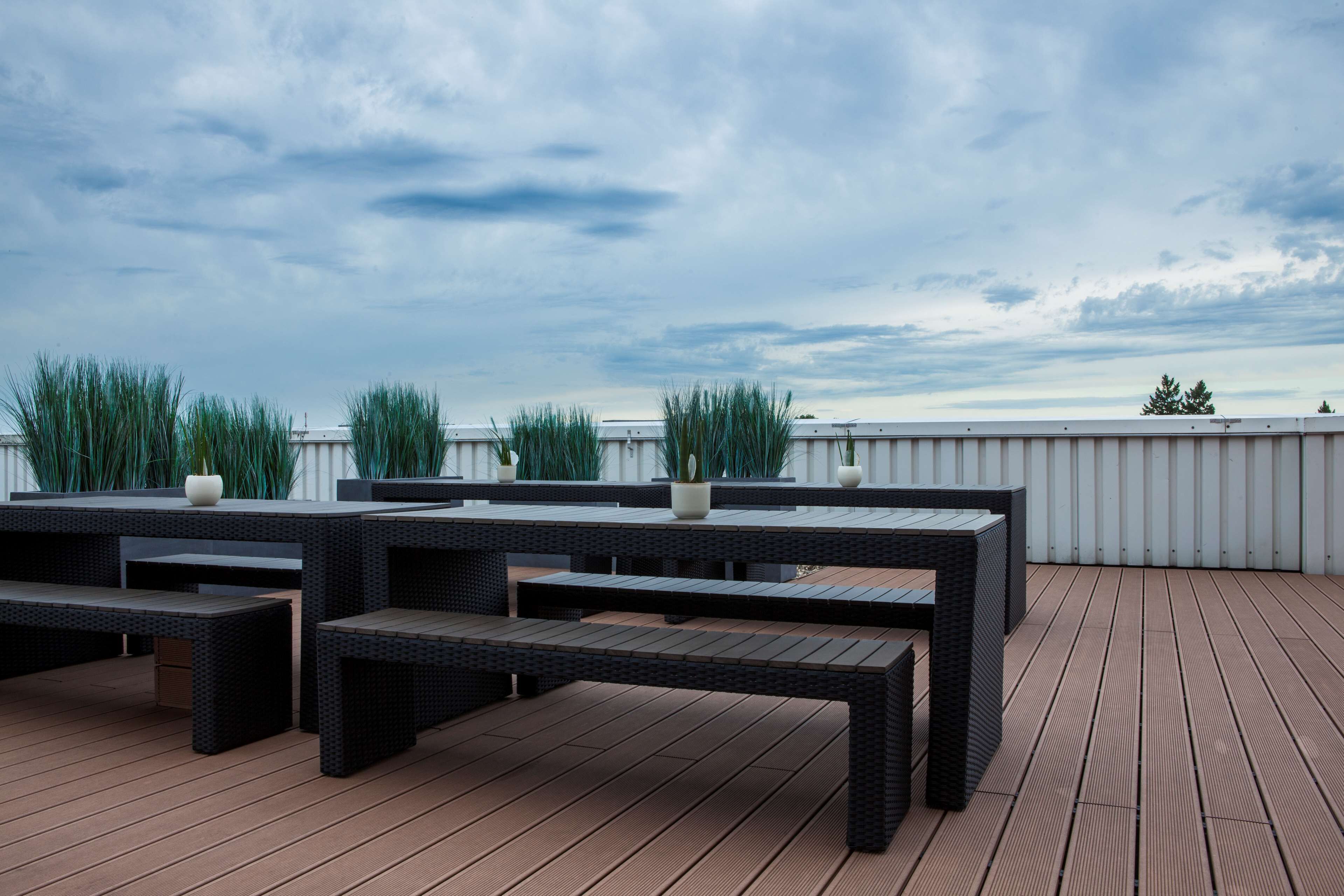 Eine Dachterrasse mit Gartenmöbeln und Topfpflanzen.