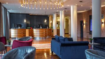 A modern lobby with a reception desk, seating area, and a brick wall.