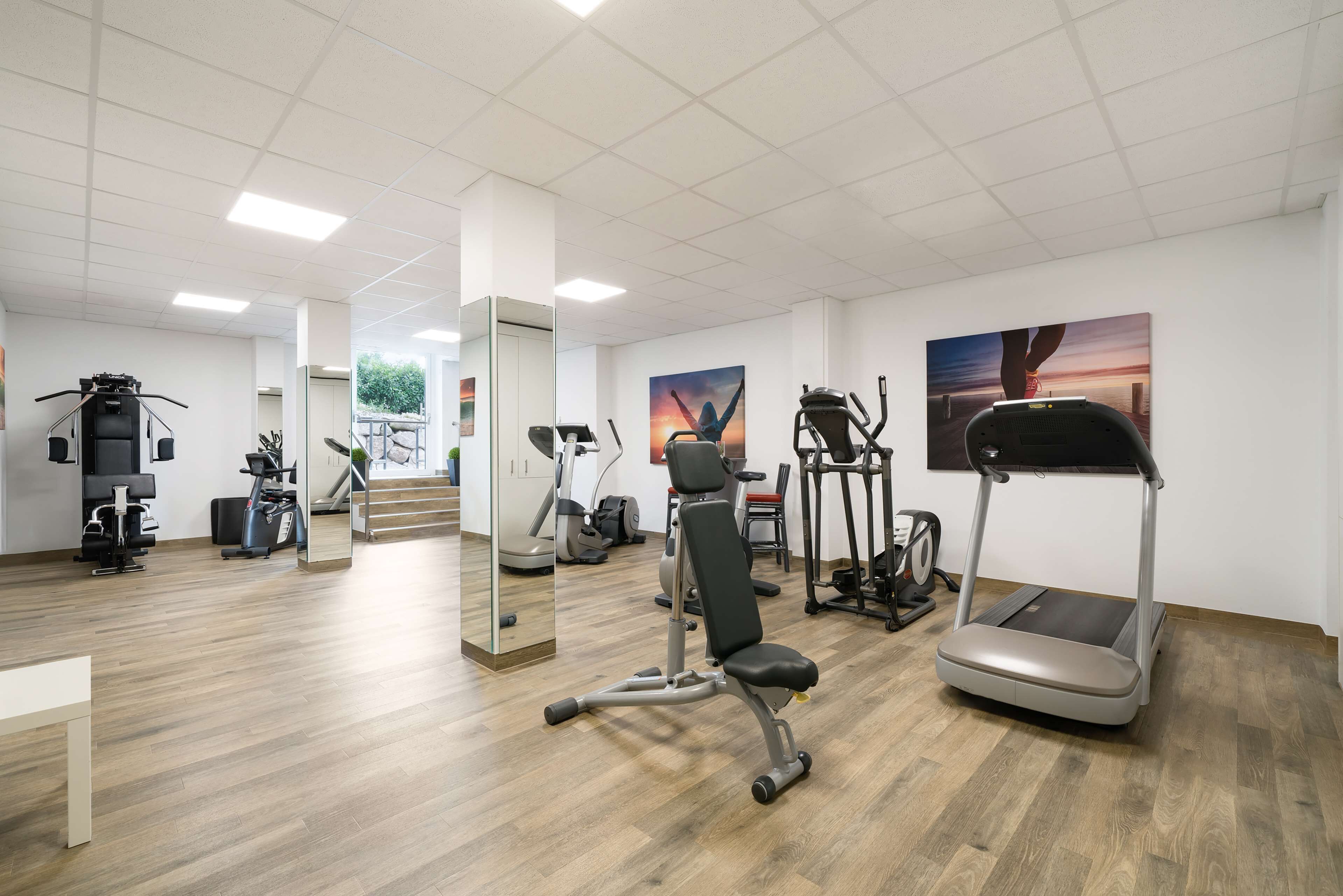 A gym with various exercise equipment, including treadmills, stationary bikes, and weight machines.