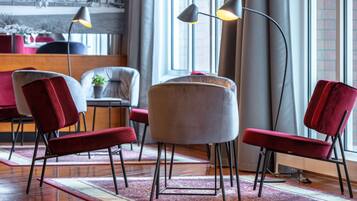 A modern interior with a seating area featuring red and grey upholstered chairs, a round table, and a floor lamp.