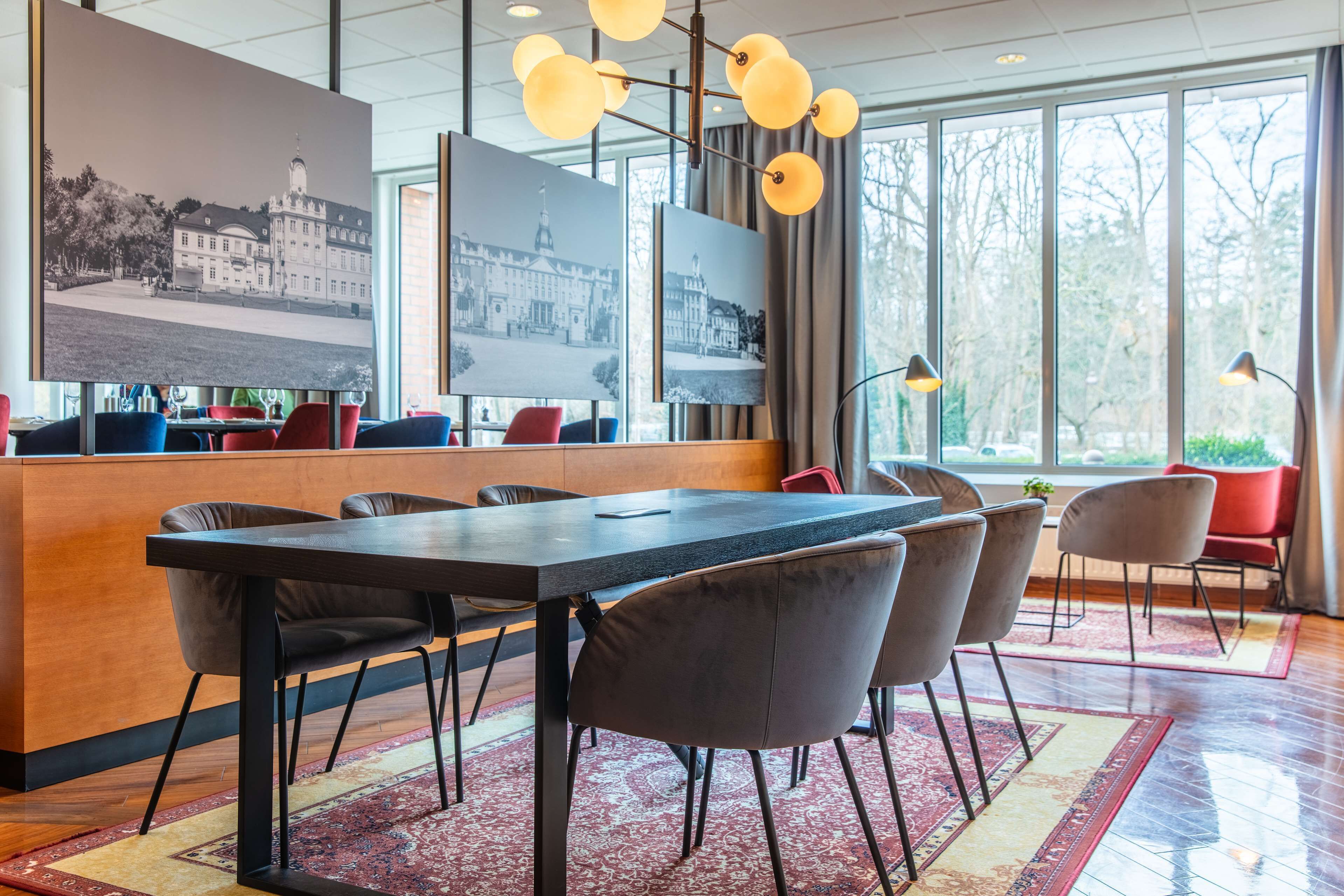 A modern hotel lobby with a long reception desk, multiple seating areas, and large windows offering a view of the outdoors.