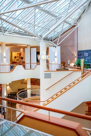 A multi-level interior with a glass ceiling, a staircase, and a dining area. - Radisson Blu Hotel, Karlsruhe (Ettlingen)