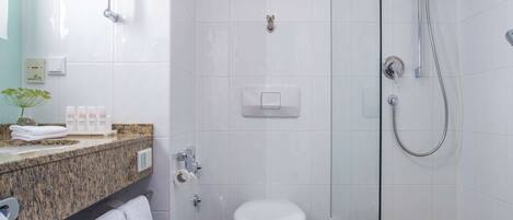 A modern bathroom with a glass-enclosed shower, a toilet, and a vanity with a granite countertop.