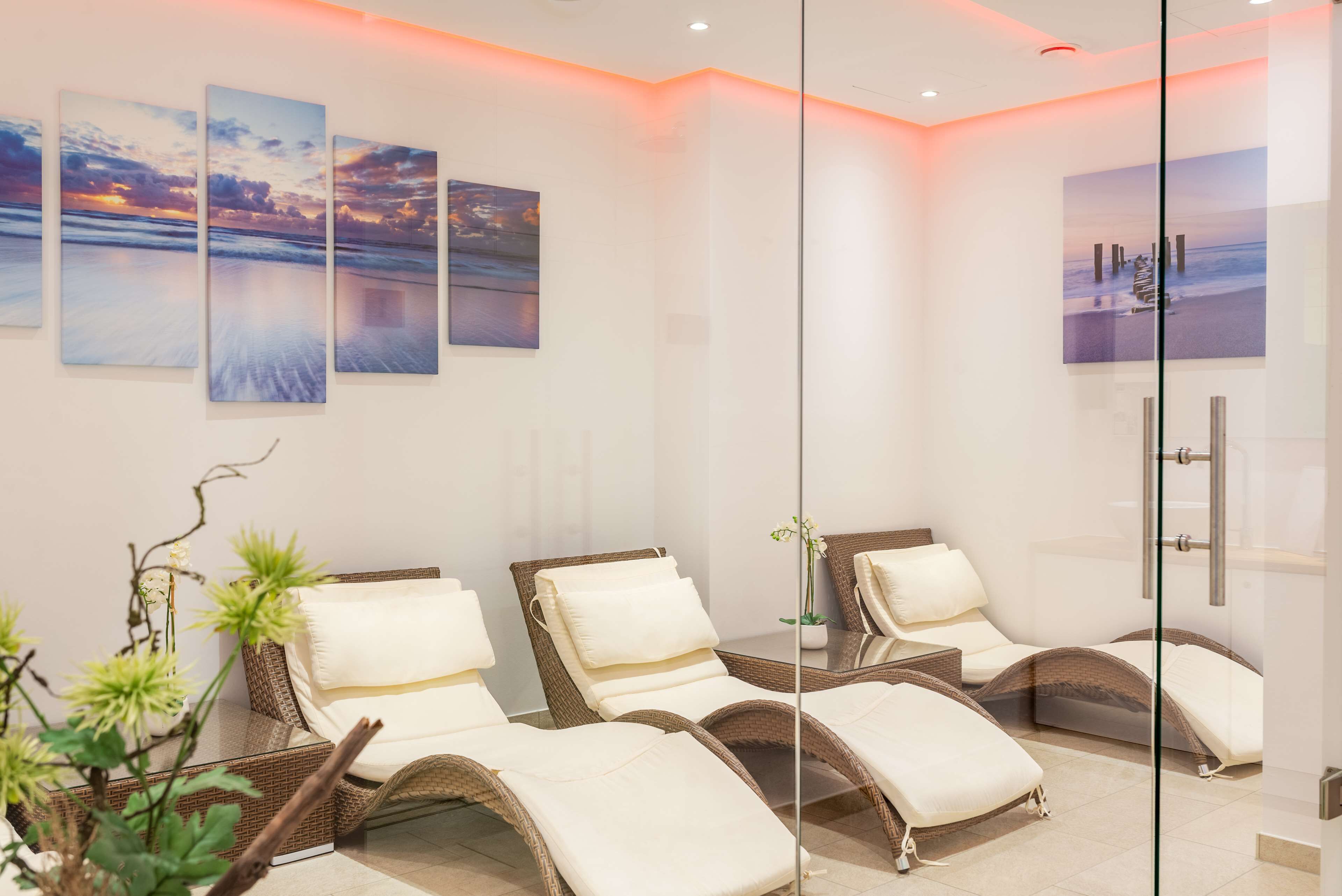 Una stanza spa con poltrone reclinabili, opere d'arte alle pareti e un divisorio in vetro.