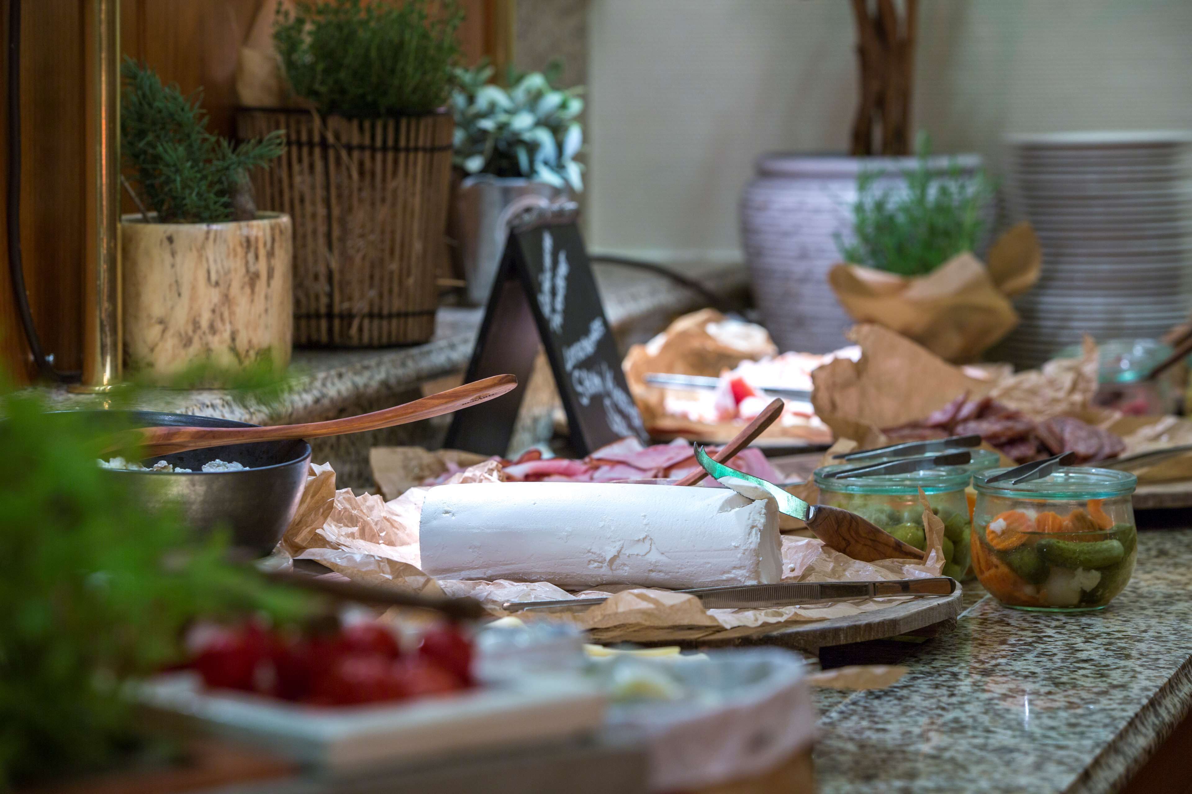 Un tavolo da buffet con diversi cibi, tra cui una torta bianca grande, vasetti di sottaceti e un cartello con scritte.