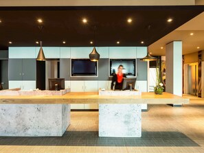 A modern kitchen with a central island, built-in appliances, and pendant lighting. - ibis München Garching (Garching)