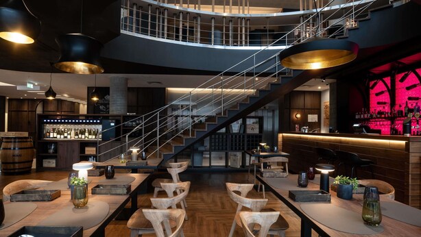 A modern bar area with a staircase, wooden furniture, and a bar counter. - Novotel Vilnius Centre (Vilnius)