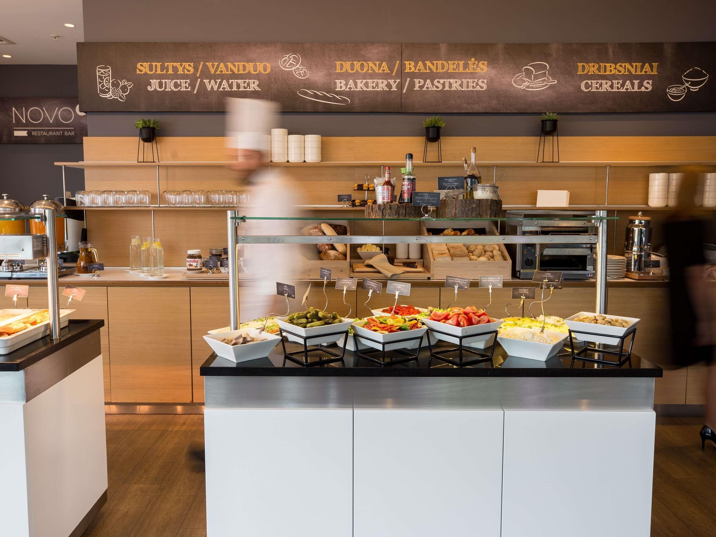 A buffet area with labeled food stations, a coffee machine, and a bakery display.