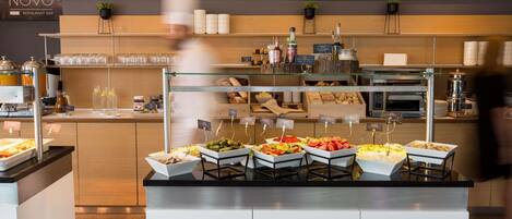 A buffet area with labeled food stations, a coffee machine, and a bakery display.