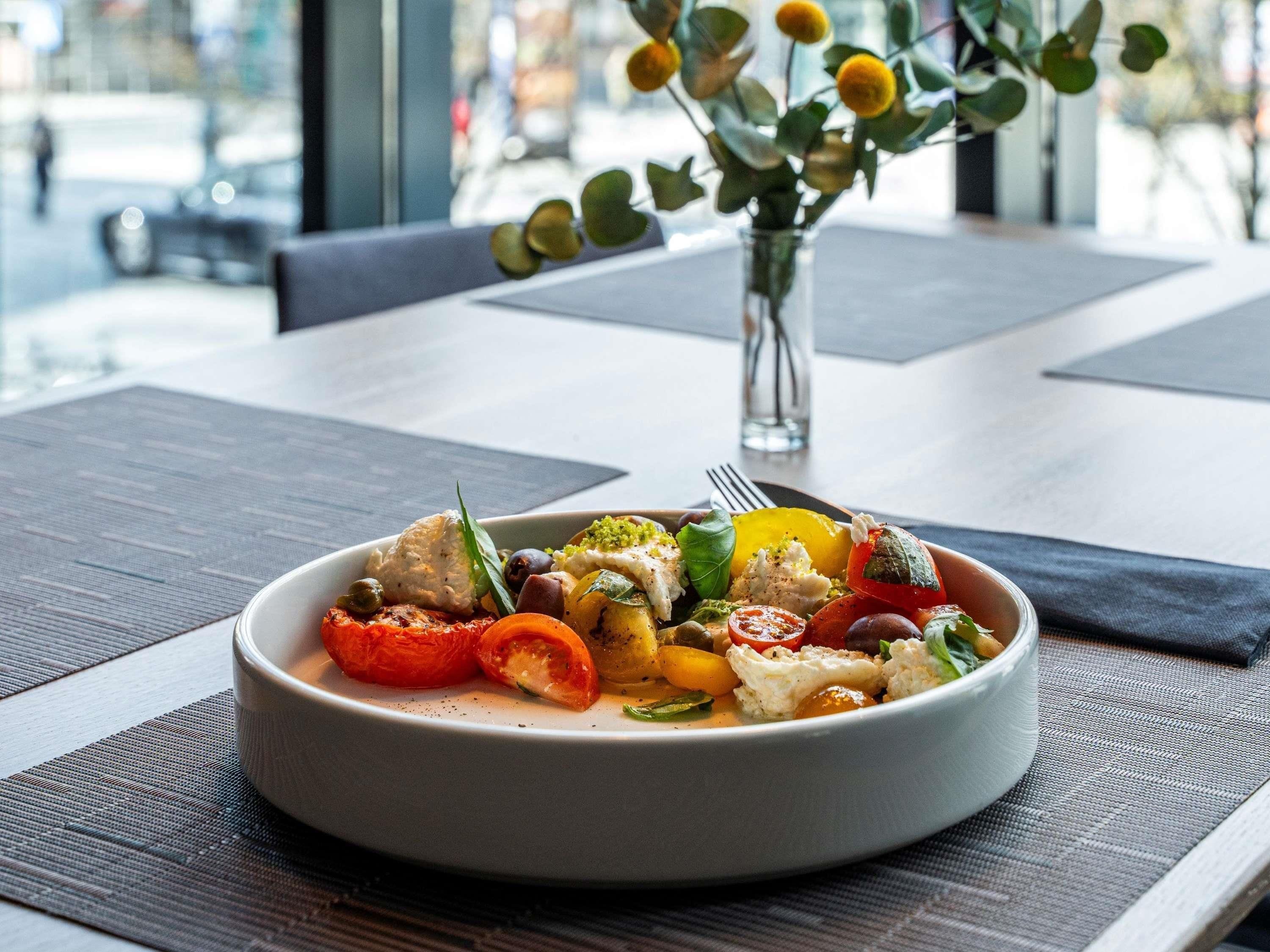 A bowl of food on a table with a vase of flowers in the background.