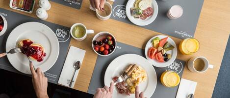 A breakfast setting with croissants, eggs, and various fruits and beverages on a table.