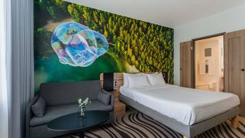 Una camera d'albergo con un letto, un divano, un tavolino e un affresco sulla parete.