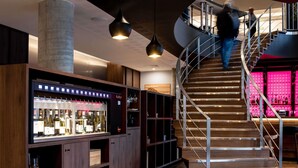 A modern interior with a spiral staircase, a wine refrigerator, and wooden shelving. - Novotel Vilnius Centre (Vilnius)