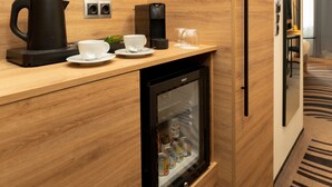 A compact kitchenette with a coffee maker, a kettle, a glass, and a mini-fridge. - Novotel Vilnius Centre (Vilnius)