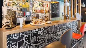 Un área de bar moderna con mostrador, asientos y una pared decorada con arte abstracto.