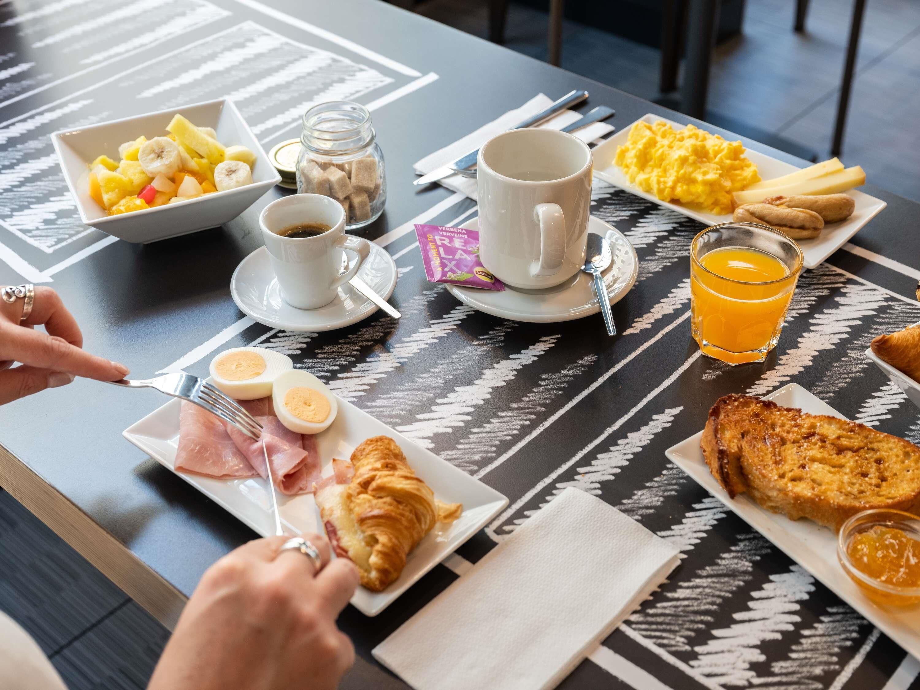 Desayuno con una variedad de alimentos, como huevos, tostadas y fruta.