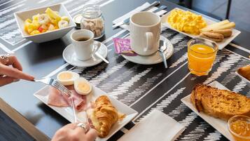 Desayuno con una variedad de alimentos, como huevos, tostadas y fruta.