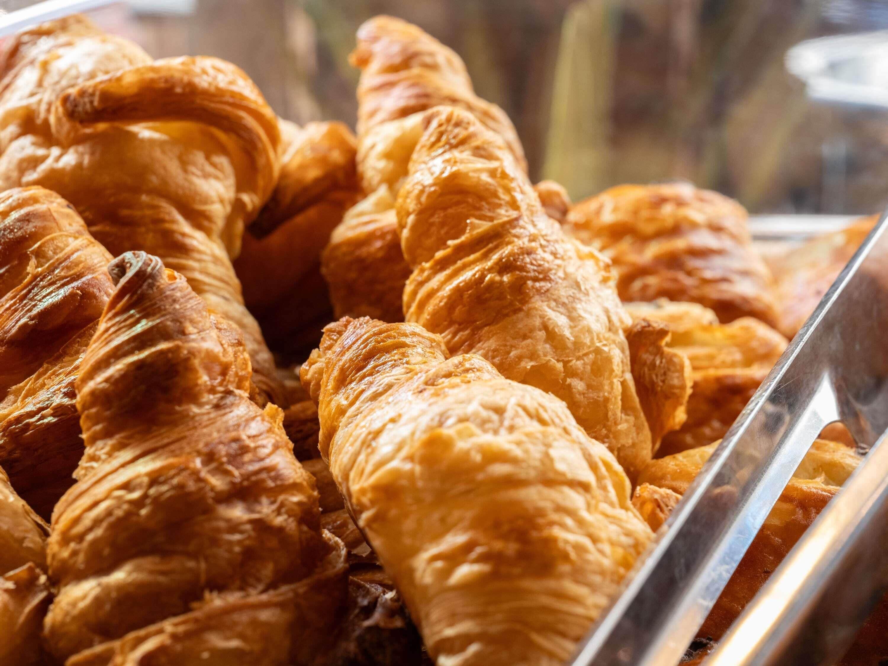 A display of golden-brown croissants in a bakery.