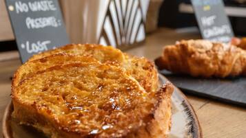 Ein Teller mit French Toast und Sirup, ein Croissant und ein Schild, das darauf hinweist, dass kein Müll vorhanden ist.