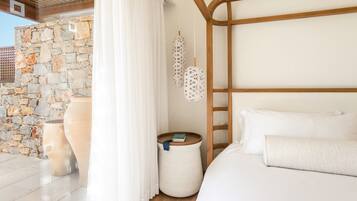 Un dormitorio con pared de piedra, cabecero de madera, un jarrón grande y una mesita de noche con un libro.
