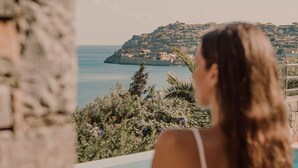 A person sitting by a pool with a view of a coastal landscape.