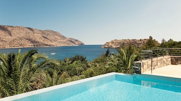 Una piscina al aire libre, sombrillas, sillones reclinables de piscina