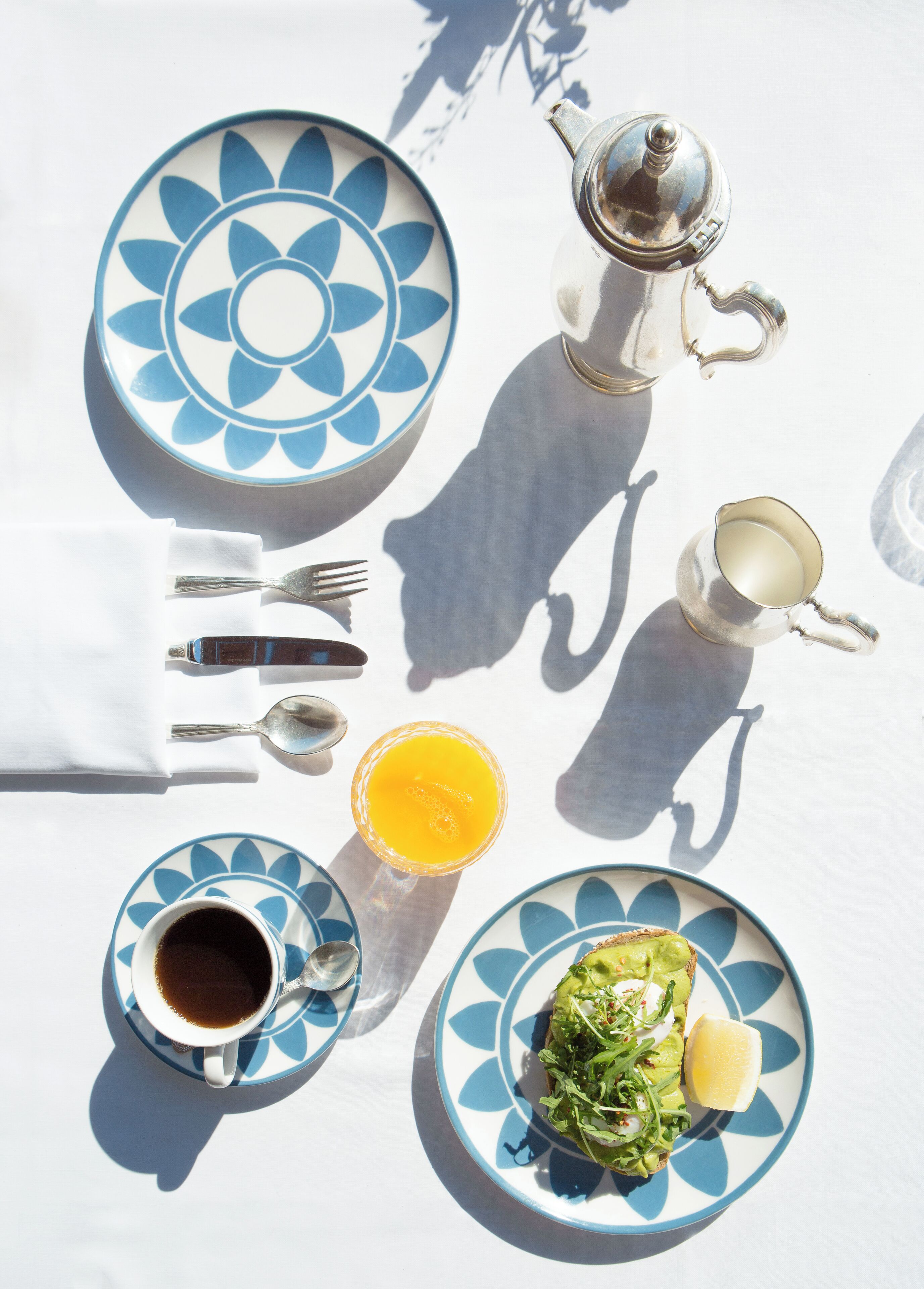 Una preparación para el desayuno con una taza de café, un vaso de jugo y un plato con ensalada verde.