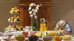A breakfast buffet with various food items and a decorative vase of white flowers. - Hotel Stendhal (Rome)