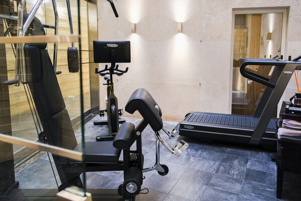 Un gimnasio con equipo de ejercicio, incluyendo una caminadora, banco de pesas y bicicleta estática.
