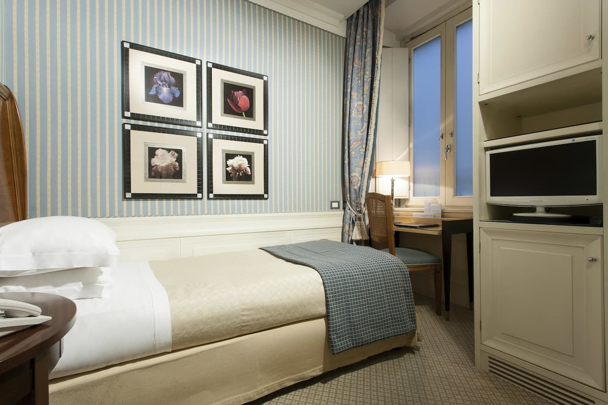 Ein Hotelzimmer mit einem Bett, einem Schreibtisch, einem Fernseher und gerahmten Bildern an der Wand.