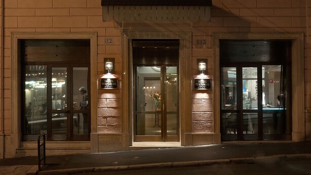 A hotel entrance with glass doors, numbered 112 and 113, and a visible interior through the glass. - Hotel Stendhal (Rome)