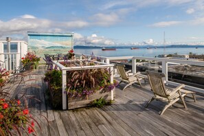 Una terraza de madera con asientos exteriores y una jardinera con flores.