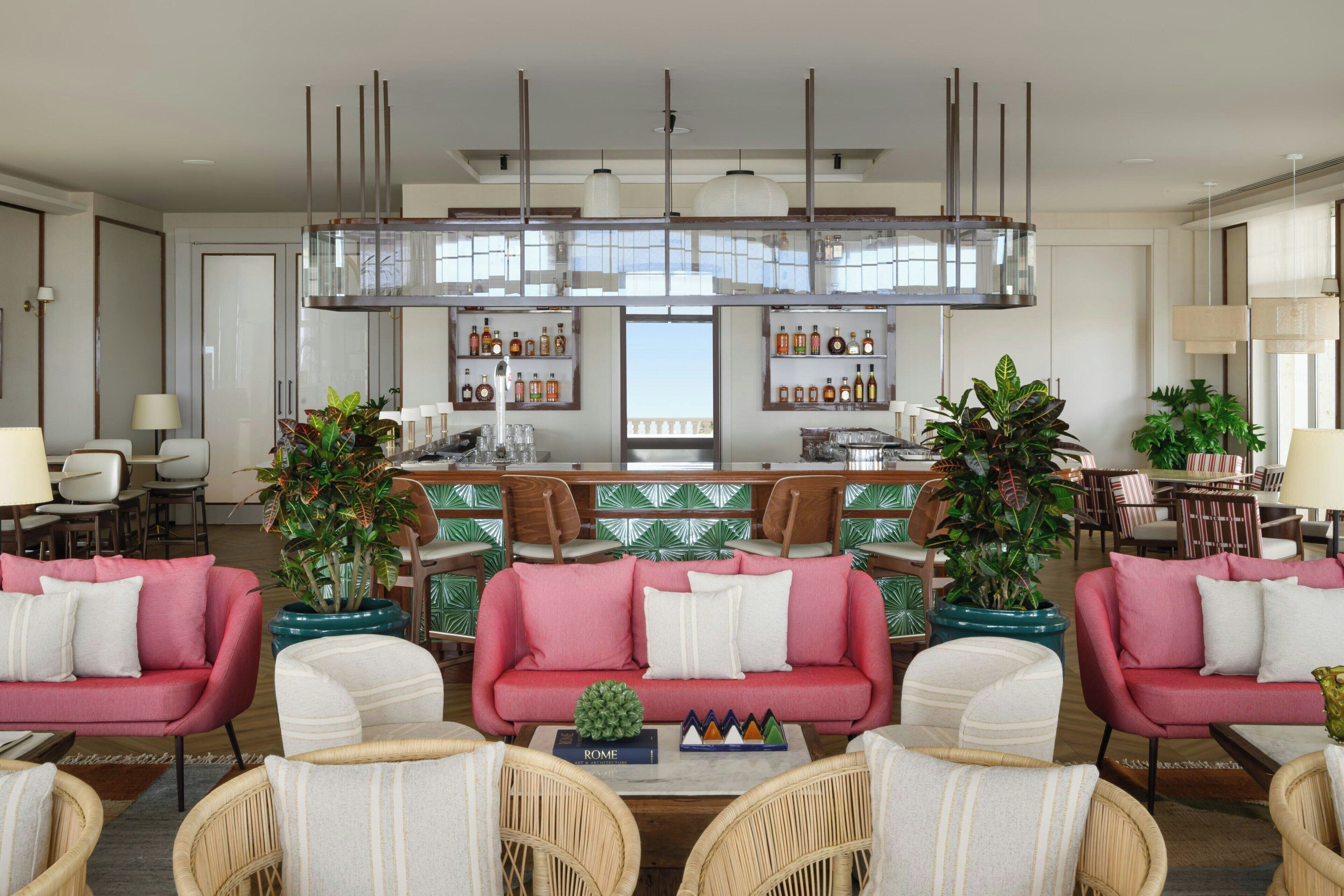 A spacious living area with a central bar, multiple seating options, and a view of the outdoors.