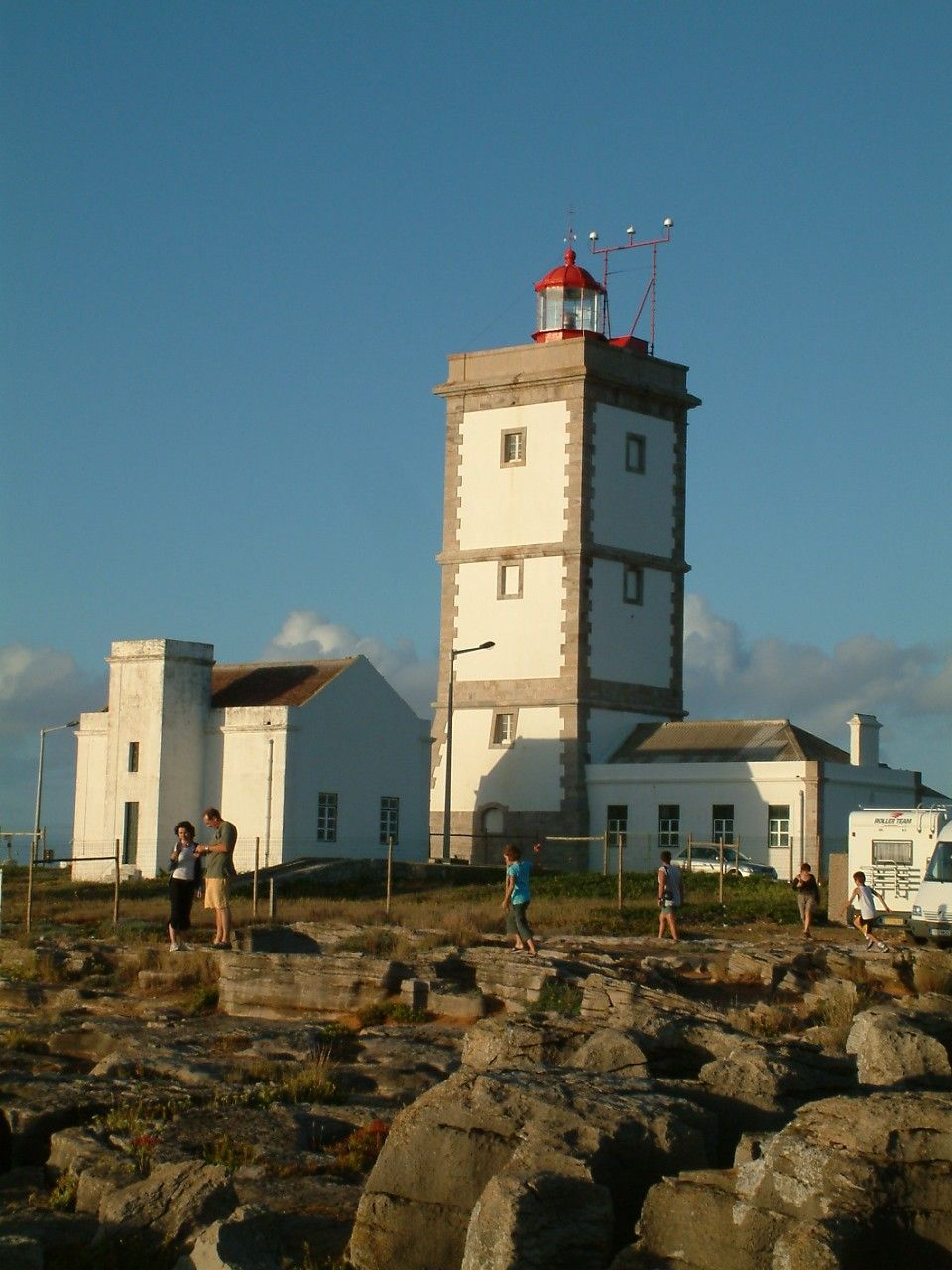 A coastal building with a prominent tower, a small balcony, and a flagpole.
