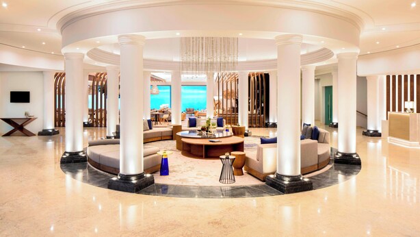 A spacious lobby with a circular seating area, large columns, and a view of the sea. - Praia D'El Rey Marriott Golf & Beach Resort (Obidos)