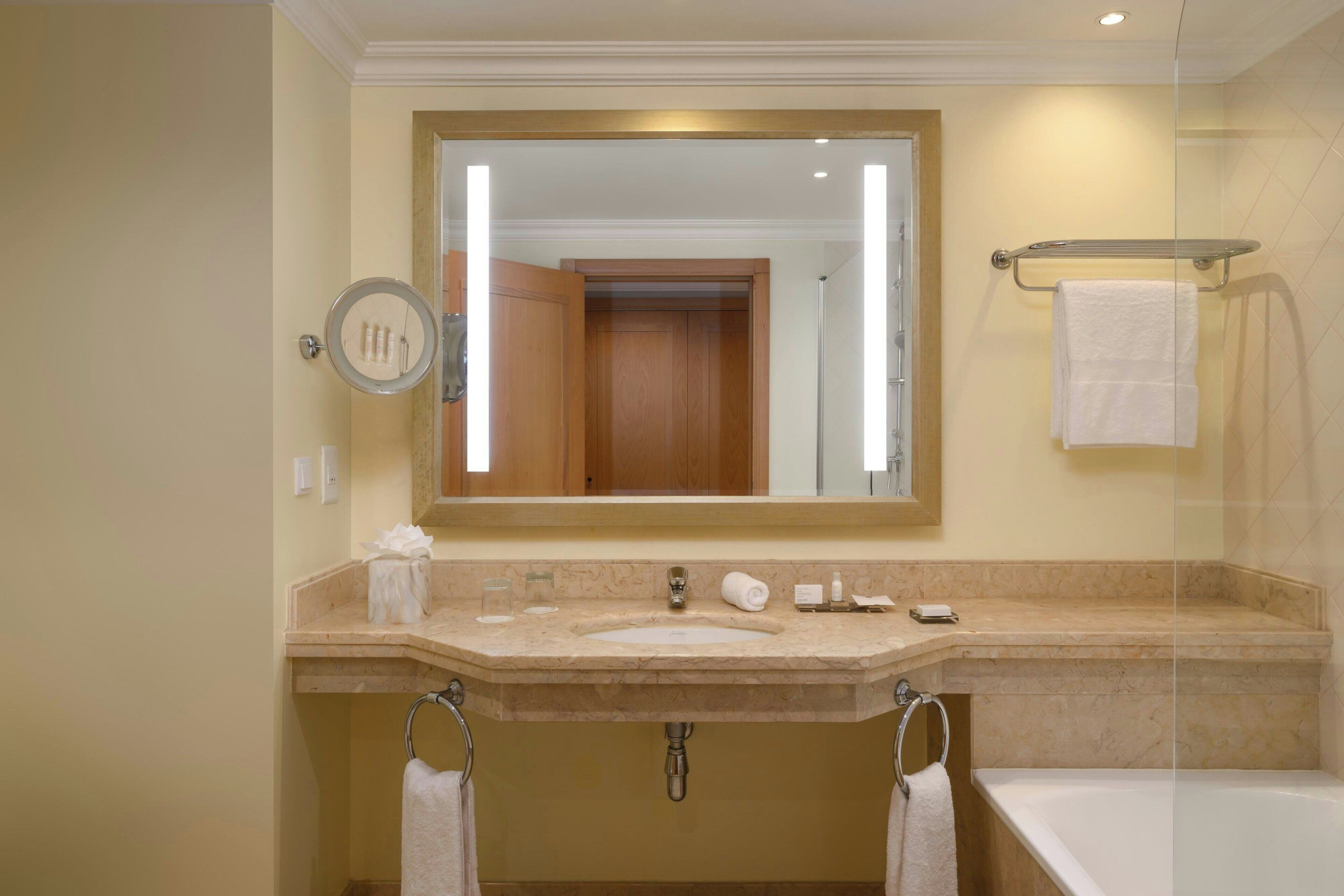 Un baño con lavamanos, espejo y bañera.
