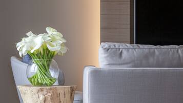 Un salon moderne avec un canapé gris, une table d’appoint en bois et un vase rempli de fleurs blanches.