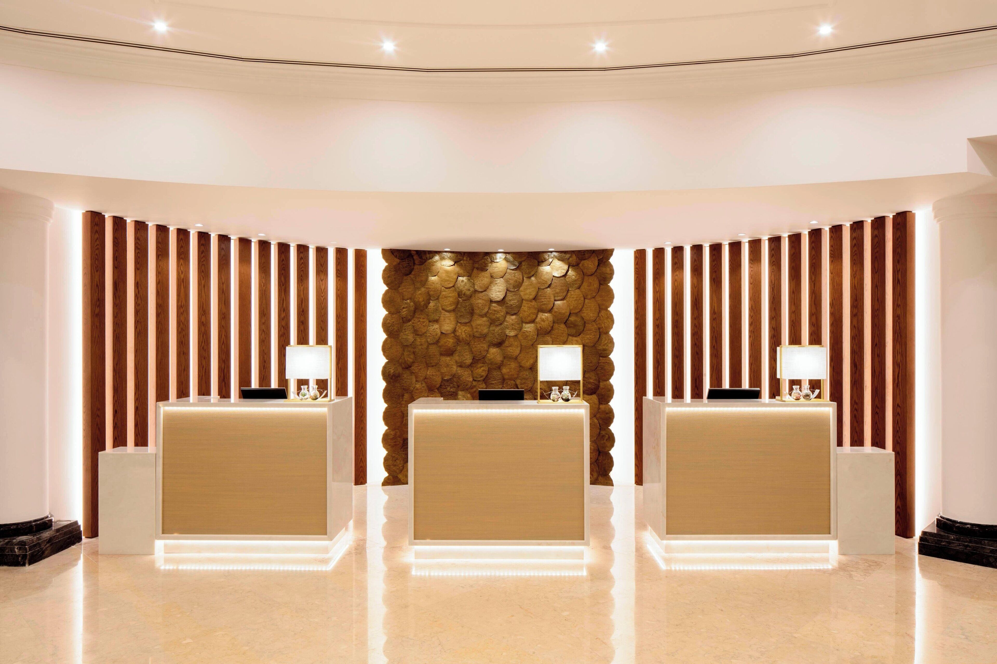 A reception area with three reception desks, a stone wall, and wooden paneling.