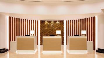 A reception area with three reception desks, a stone wall, and wooden paneling.