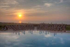 Una piscina techada, una piscina al aire libre, sombrillas