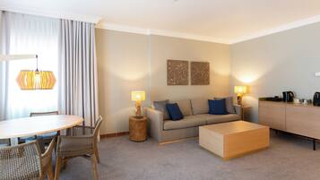 Ein modernes Wohnzimmer mit rundem Tisch, Korbstühlen, einer Couch, einem Couchtisch und zwei Lampen.