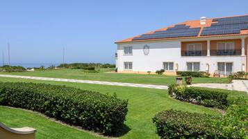 Un edificio de dos plantas con techo de tejas, paneles solares y un césped bien cuidado.