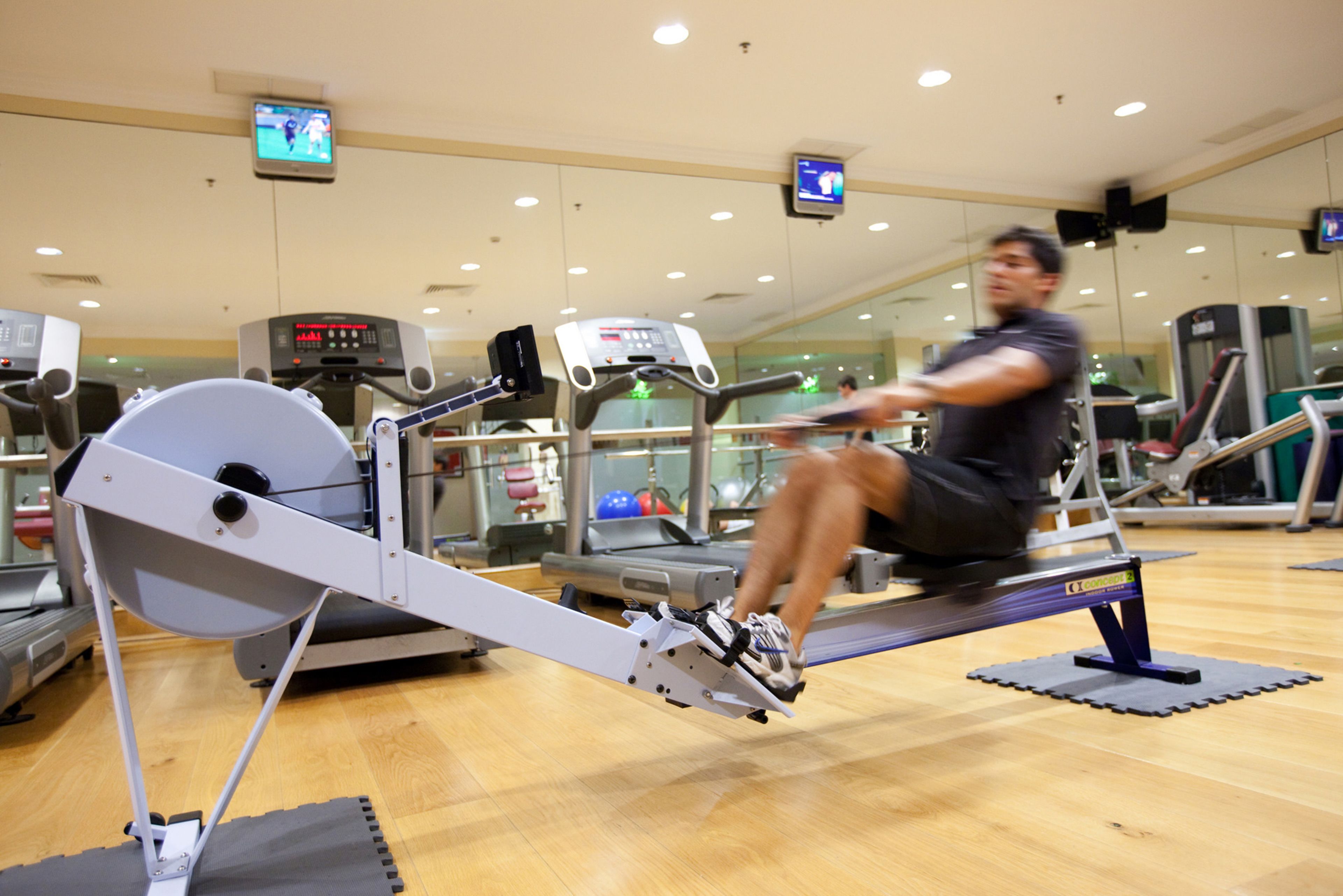 Un gimnasio con equipo de ejercicio, incluyendo una máquina de remo y cintas de correr.