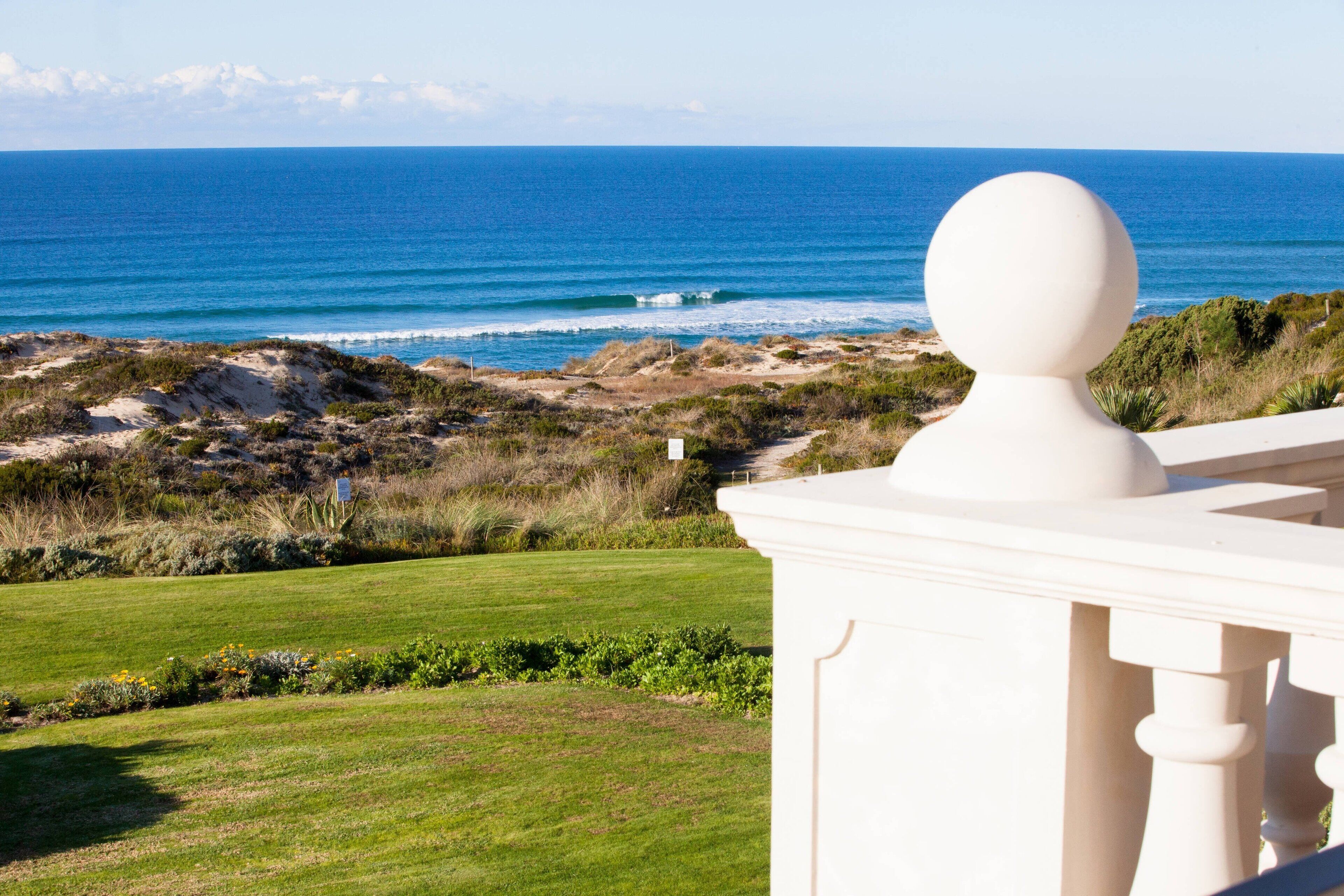 Vista costera con balaustrada blanca y una escultura de busto.