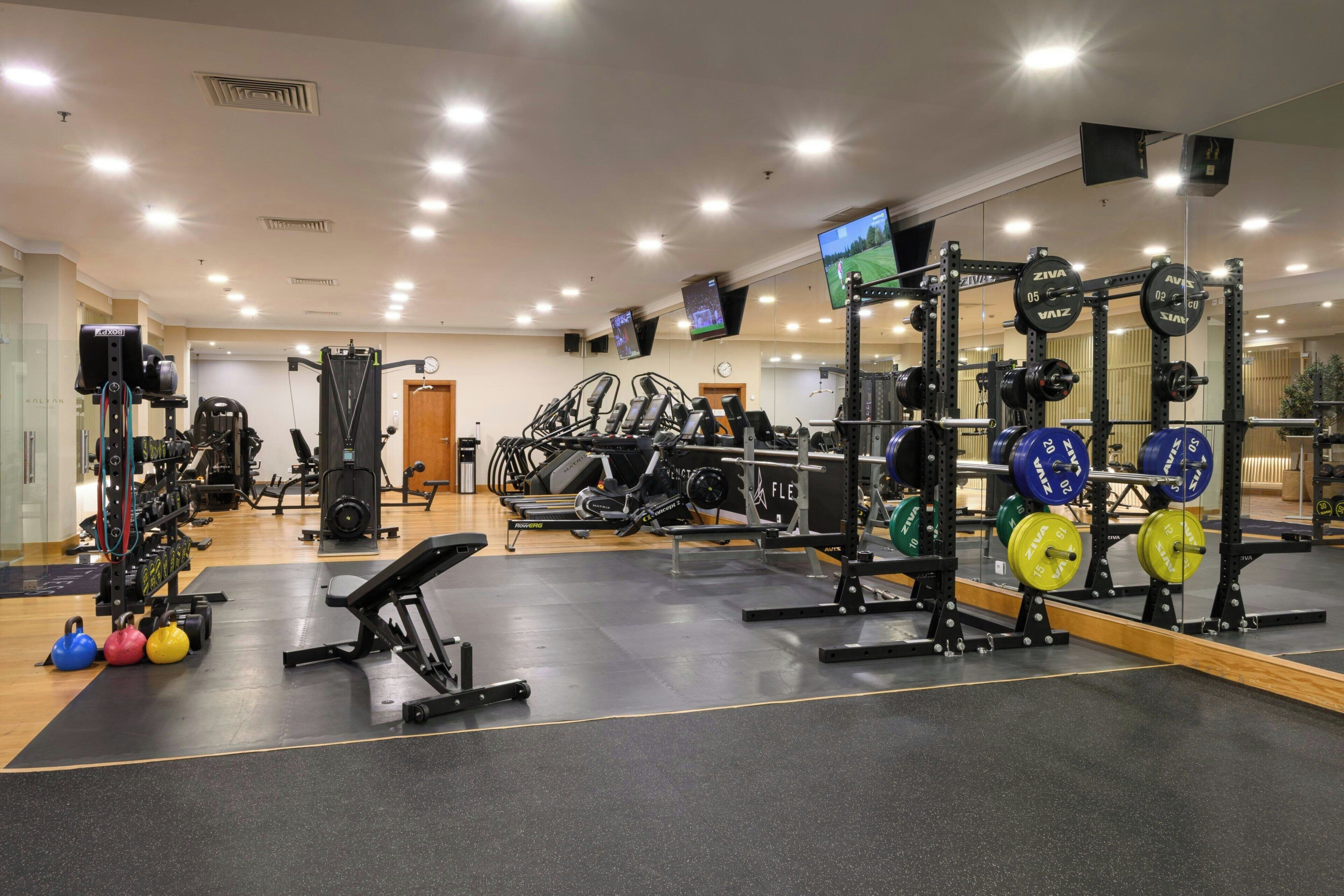 A gym with various exercise equipment, including weight machines, free weights, and cardio machines.
