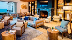 A spacious living area with a fireplace, comfortable seating, and a view of the sea. - Praia D'El Rey Marriott Golf & Beach Resort (Obidos)
