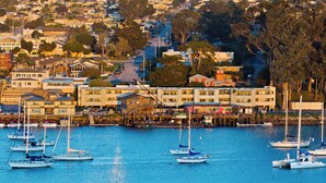 A coastal town with a marina, buildings, and a hilly backdrop. - 456 Embarcadero Inn & Suites (Morro Bay)