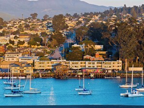 A coastal town with a marina, buildings, and a hilly backdrop. - 456 Embarcadero Inn & Suites (Morro Bay)