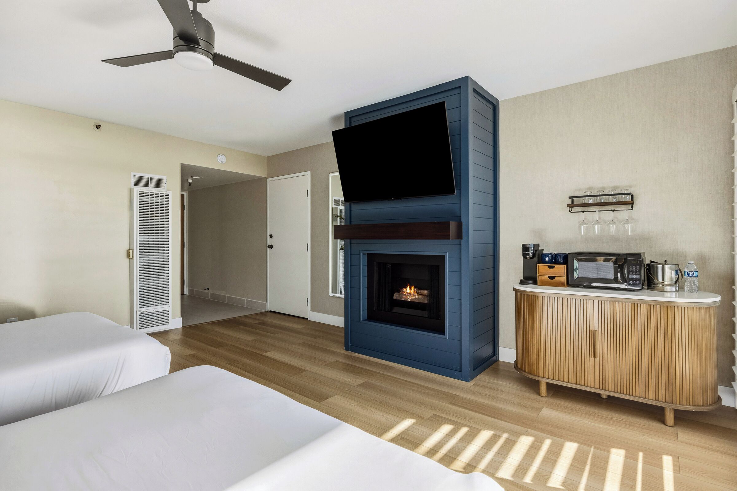 A hotel room with a fireplace, a television, a minibar, and two beds.