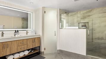 Un baño moderno con un espejo grande, tocador de madera y cabina de ducha de vidrio.